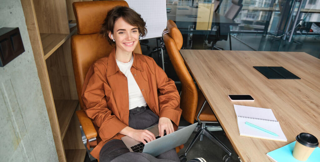 Business and lifestyle concept. Young woman in casual clothes, working on laptop, sitting in office. Журналист