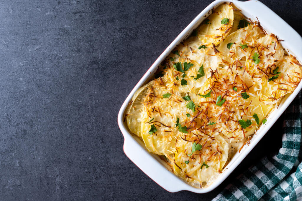 Potato gratin baked with cream and cheese on wooden table. Журналист