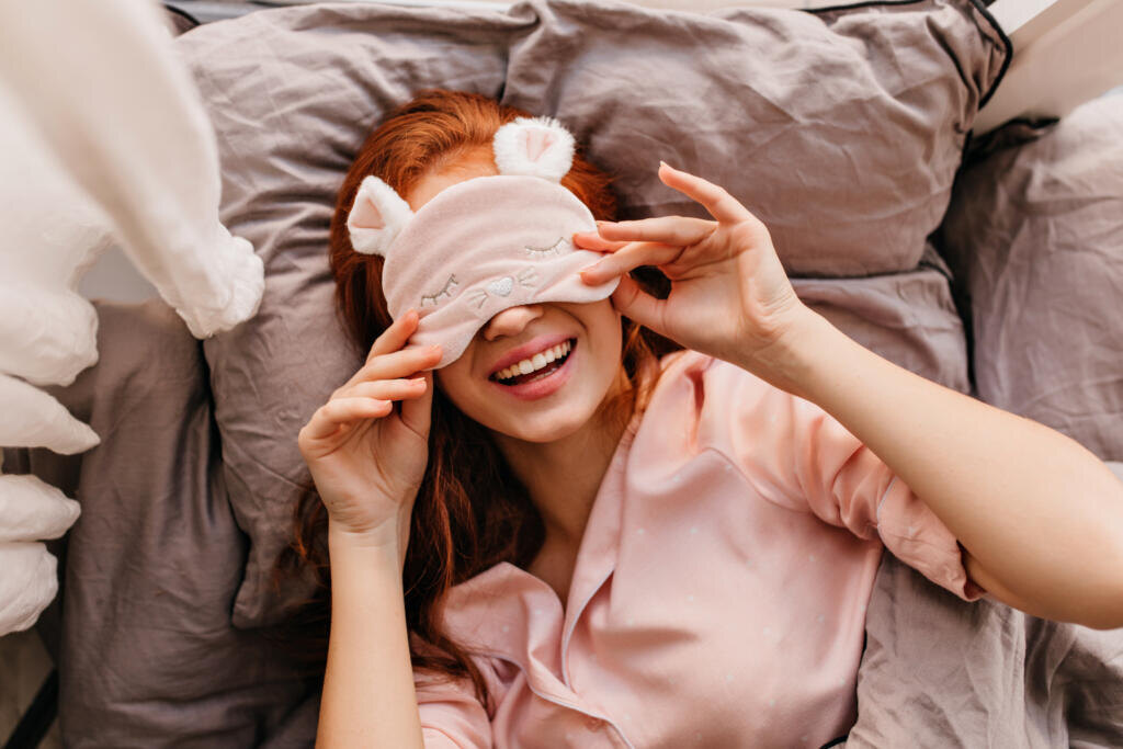 Romantic girl lying in bed with inspired smile. Overhead shot of good-humoured ginger lady. Журналист