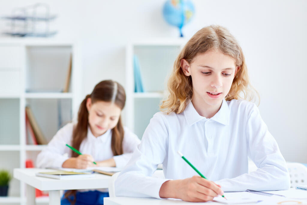 Little learners drawing with pencils or making notes during exam Журналист