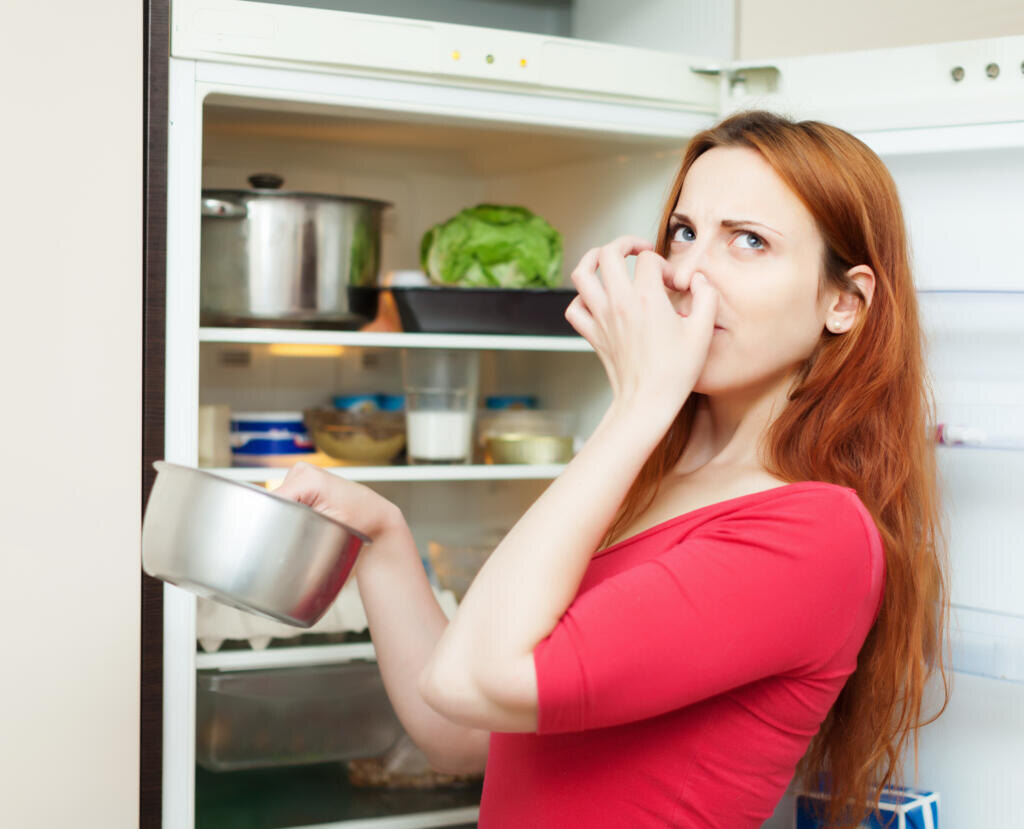woman in red holding foul food near refrigerator Журналист