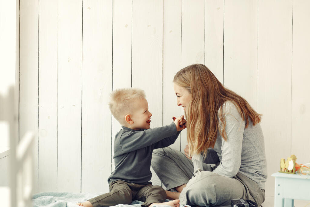 Beautiful woman with child. Woman in a gray sweater. Family sitting on a floor. Журналист