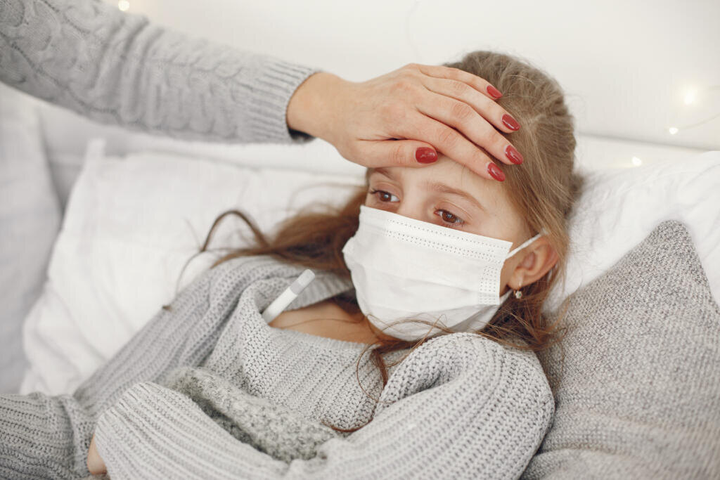 Coronavirus in a child. Mother with daughter. Child lying in a bed. Woman in a medical mask. Журналист