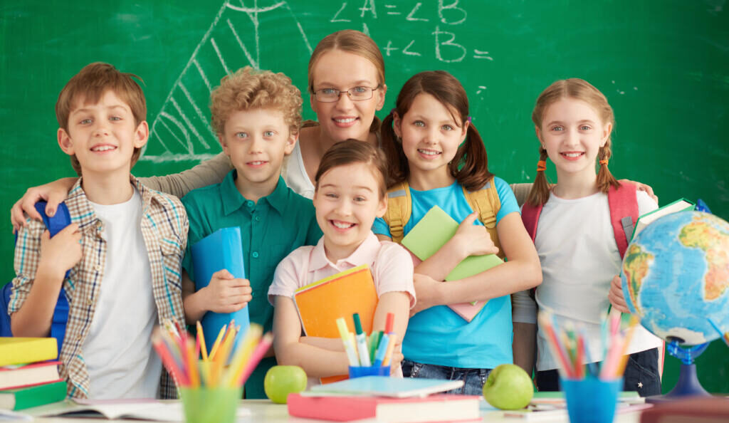 Portrait of cute schoolchildren and their teacher on background of blackboard Журналист