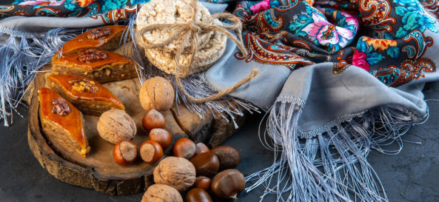 side view of baklava with whole nuts and rice breads on a shawl with tassel Журналист