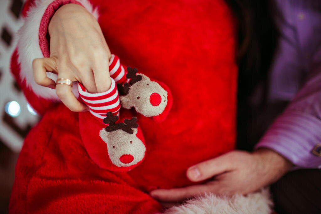 Man holds little red shoes on woman's belly Журналист