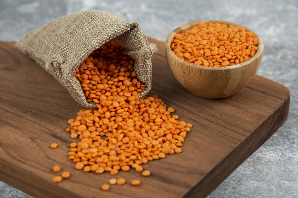 Bowl and sackcloth of red raw lentils on wooden board. High quality photo Журналист
