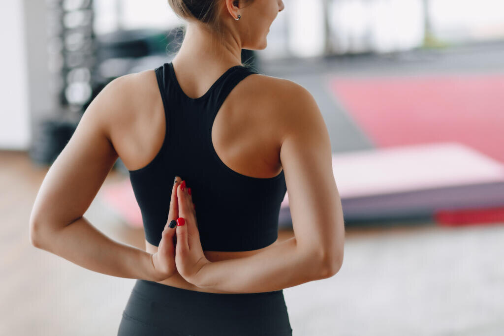 hands folded behind her back, young girl in gym during yoga class Журналист