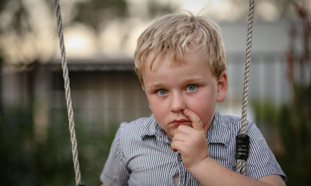 A portrait of a little boy sitting in a pretty garden setting Журналист