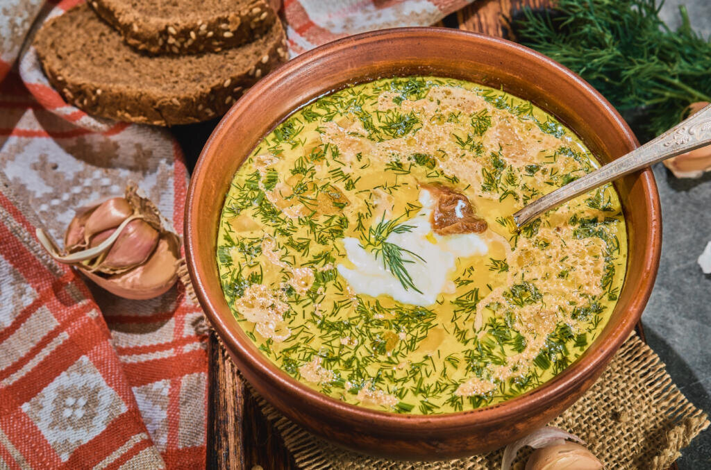 Chowder with vegetables and mushrooms, and chicken meat, Close-up with selective focus. Soup plate is served with black bread, sour cream and garlic. A healthy hot winter lunch. Журналист