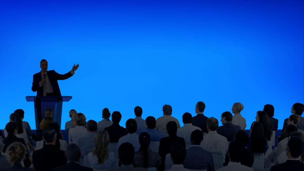 Corporate businessman giving a presentation to a large audience Журналист