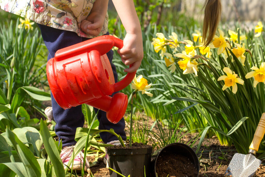 Little girl planting flowers in the garden, Earth Day. Kid helping at the farm. Журналист