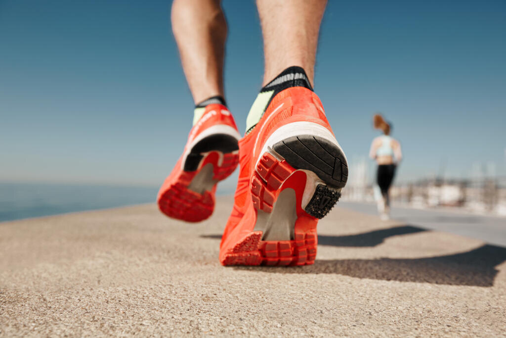 Close up runner feet. Man runner legs and shoes in action on road outdoors at road near sea. Male athlete model. Журналист